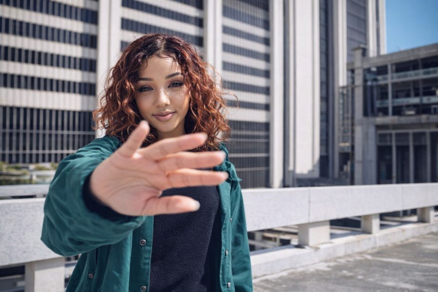 Nastolatka w zielonej kurtce z Kids Brand Store na tle architektury.